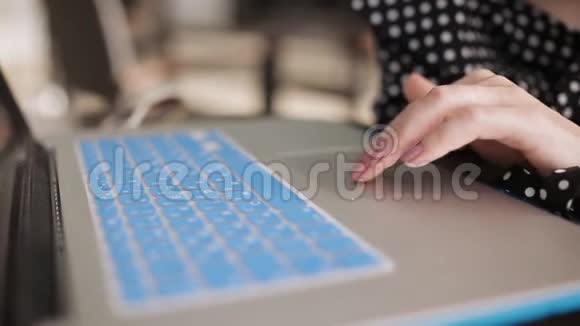 一位年轻女士在咖啡馆里用现代蓝色笔记本电脑工作视频的预览图
