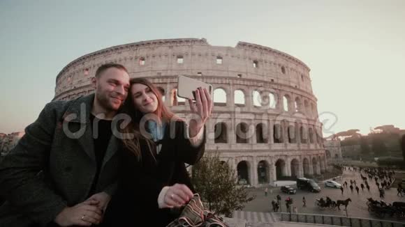 快乐的年轻夫妇在意大利罗马斗兽场附近自拍英俊的男人吻女人微笑视频的预览图