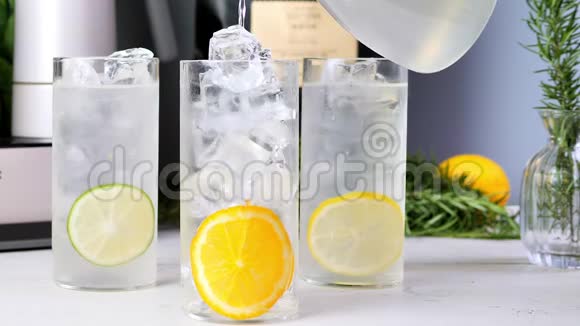把椰子汁从水壶里倒入装满冰块和柠檬片的杯子里夏天的饮料慢动作视频的预览图