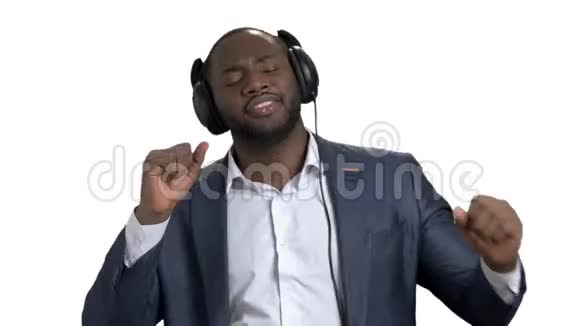 穿商务西装的黑人带着耳机听音乐视频的预览图