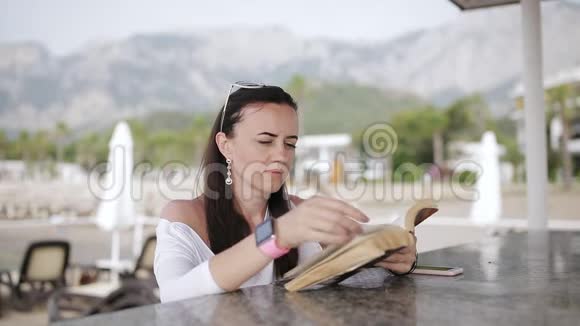 酒吧码头上的现代女人在读一本纸书视频的预览图