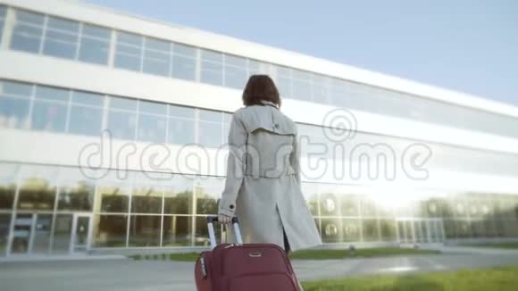 一个带着手提箱去机场大楼的女人视频的预览图