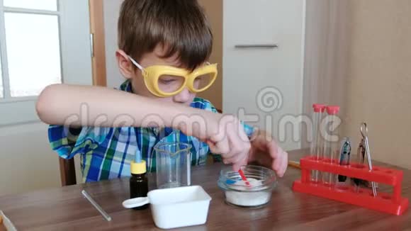 家庭化学实验男孩把物质和蓝色液体混合在烧杯里视频的预览图