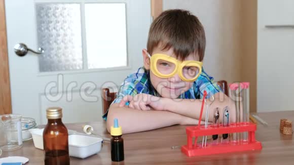 家庭化学实验穿格子衬衫的男孩坐在桌子旁准备做化学实验视频的预览图