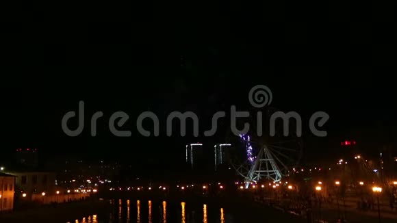 在摩天轮背景下夜空中的堤岸上放着明亮的烟花视频的预览图
