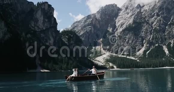 年轻夫妇在湖中央的木船放松在阳光明媚的日子一起旅行慢动作视频的预览图