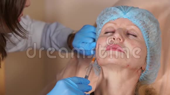 美容师医生把套管注入一位中年妇女的脸颊视频的预览图