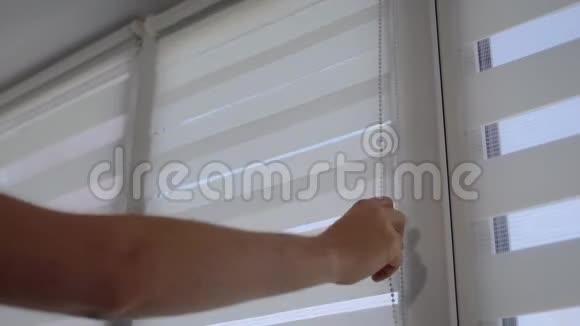 一个男人的手打开窗户上条纹百叶窗的特写镜头视频的预览图