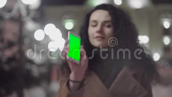 年轻女孩晚上拿着绿色屏幕的智能手机休闲生活方式视频的预览图
