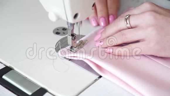 在缝纫机上用美甲缝制织物特写女性手视频的预览图