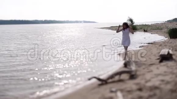 一个穿着白色连衣裙的女孩沿着水边奔跑视频的预览图