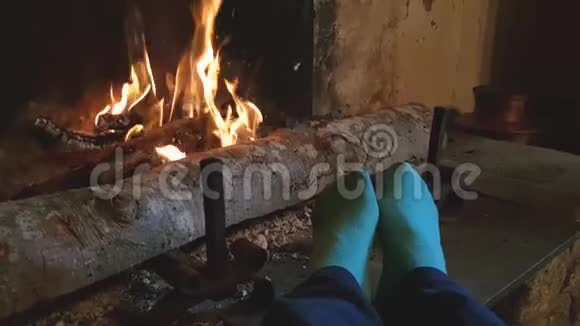 穿着蓝色袜子的腿被燃烧的壁炉的火加热视频的预览图