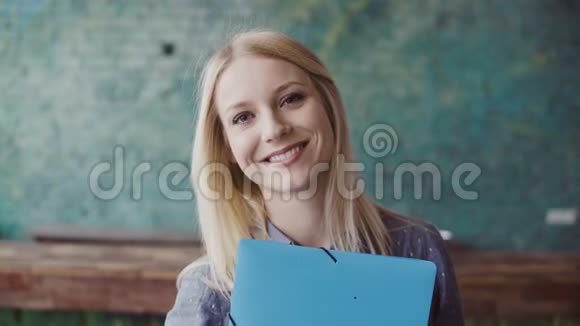 年轻的白人金发女人在现代办公室里看着镜头微笑的照片成功的员工视频的预览图
