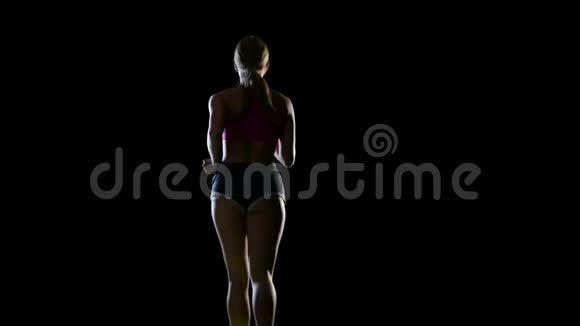 运动健身女子在黑色背景下运行后视镜剪影视频的预览图