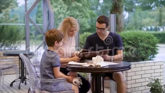 一家人坐在餐厅露台上一起从菜单中选择菜肴视频的预览图