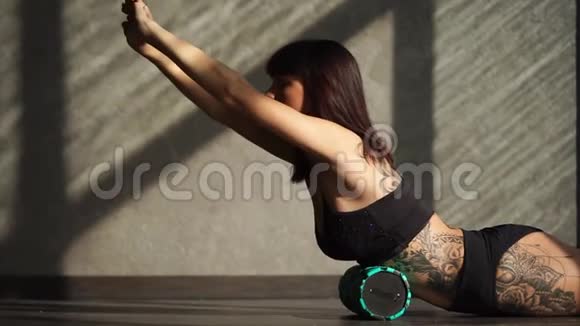 女性在健身运动中使用滚筒在背部肌肉上做运动视频的预览图