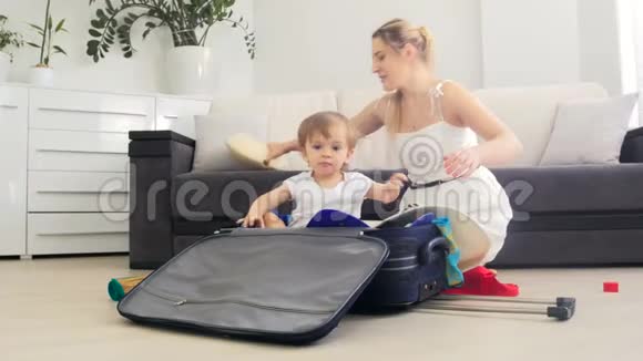 快乐的年轻妈妈带着她蹒跚学步的儿子打包暑假旅行箱视频的预览图