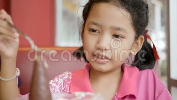 慢动作亚洲小女孩快乐地吃冰淇淋视频的预览图