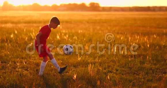 日落时分一名男孩足球运动员在球场上抛球视频的预览图