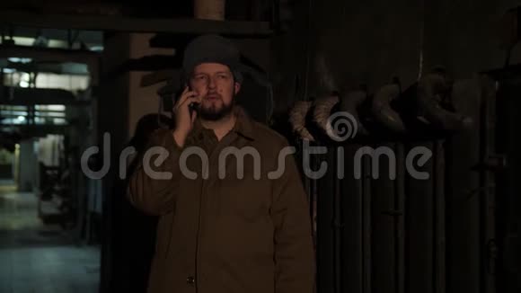 俄罗斯男人戴着一顶带耳罩的帽子在黑暗的地下室里打电话决定国家大事视频的预览图