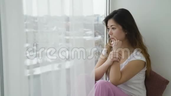 放松休闲的年轻忧郁的女孩看窗视频的预览图