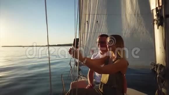 年轻女子正和男朋友在游艇上用智能手机自拍视频的预览图