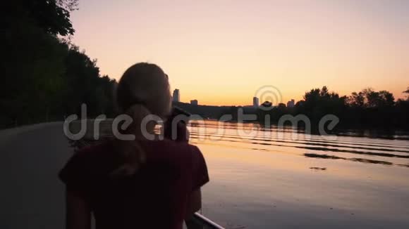 日落时分在河边散步的年轻女子视频的预览图