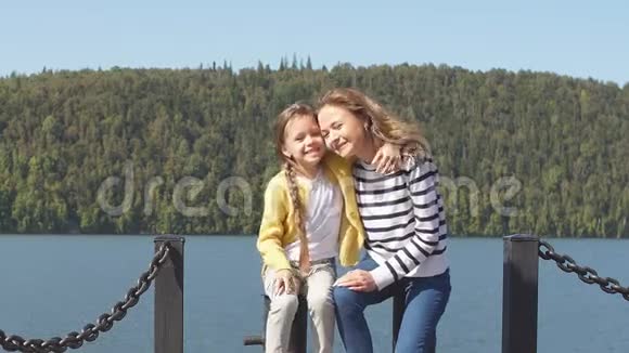 母亲和女儿坐在码头温暖的秋日视频的预览图