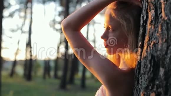 日落时分美丽的年轻女孩留着长发穿着白色连衣裙戴着帽子视频的预览图