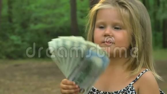 可爱的小女孩在她面前挥舞着美元视频的预览图
