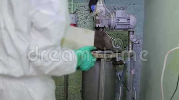 实验室工作人员将白色粉末从托盘中倒入工厂地下室的大钢罐中视频的预览图