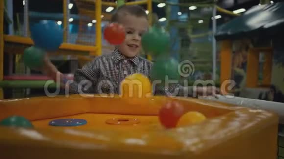 三岁的男孩在游泳池里玩着五颜六色的塑料球视频的预览图