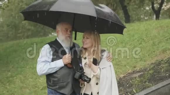 幸福的女人和年长的男人在公园的雨中散步由前男友结婚视频的预览图