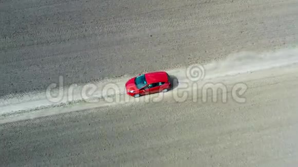 无人驾驶飞机在一辆红色汽车上沿空碎石路行驶的空中视野视频的预览图