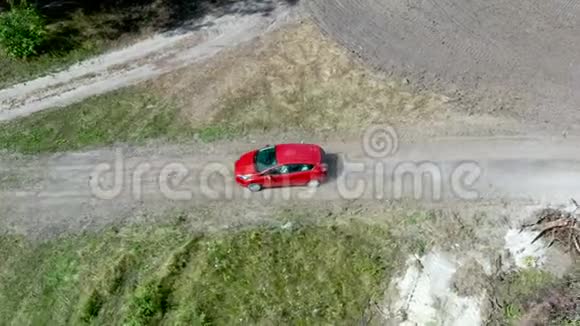 无人驾驶飞机在一辆红色汽车上沿空碎石路行驶的空中视野视频的预览图