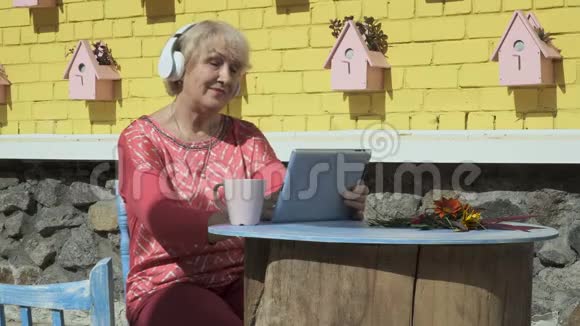 漂亮的老妇人听音乐用平板电脑视频的预览图