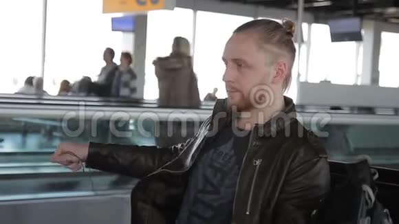 年轻人坐在机场时戴着耳机视频的预览图
