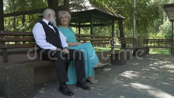 英俊的老人和漂亮的老妇人在公园的长凳上休息视频的预览图