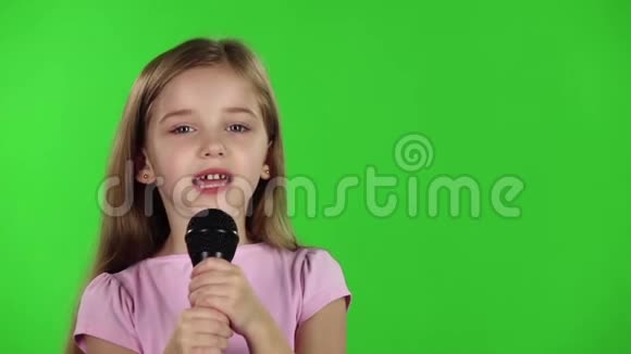 童女将歌曲唱入话筒绿色屏幕慢动作视频的预览图