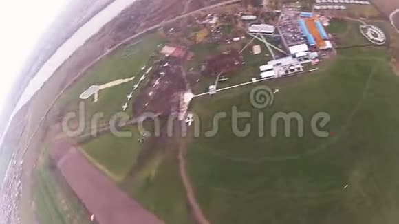 空中跳伞跳伞在多云的天空上绿色的田野城市着陆景观视频的预览图