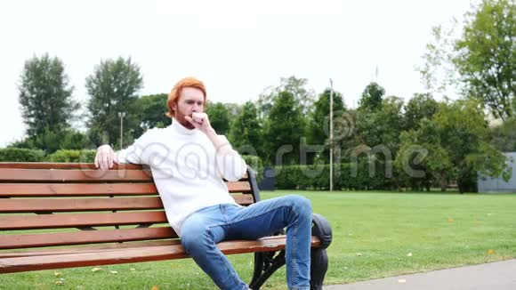 病人咳嗽坐在公园里红发和胡子视频的预览图