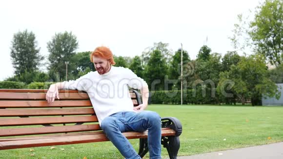 背部疼痛脊柱疼痛坐在长凳上红胡子和头发上的疲惫的人视频的预览图