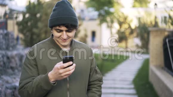 年轻的黑发男子在公园发短信视频的预览图