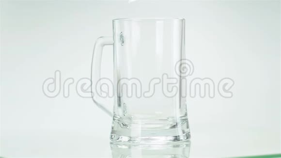 啤酒倒入玻璃杯中在墙上泡沫在白色背景上流动慢镜头拍摄视频的预览图