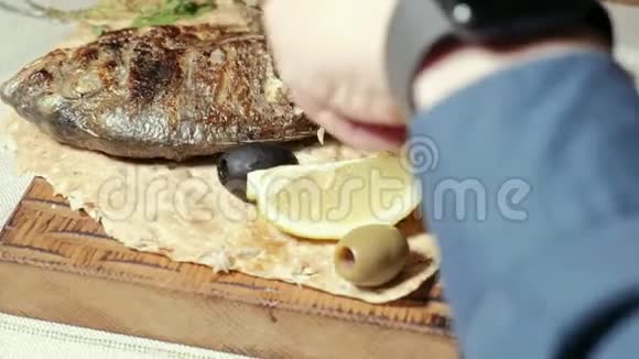 特写镜头烤鱼橄榄和皮塔面包上的一片柠檬视频的预览图