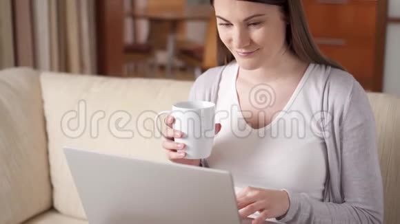 微笑的职业女性在家里用笔记本电脑工作喝咖啡家庭办公概念视频的预览图