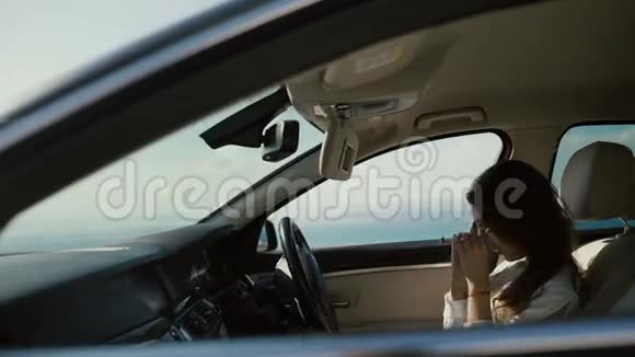 时髦的女人在驾驶座的汽车驾驶室里纠正头发视频的预览图