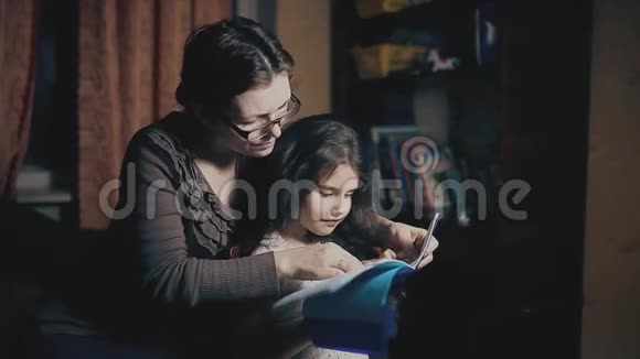 小女孩和一个成年女人正在读一本书他们在晚上被教一个睡前故事母亲和视频的预览图