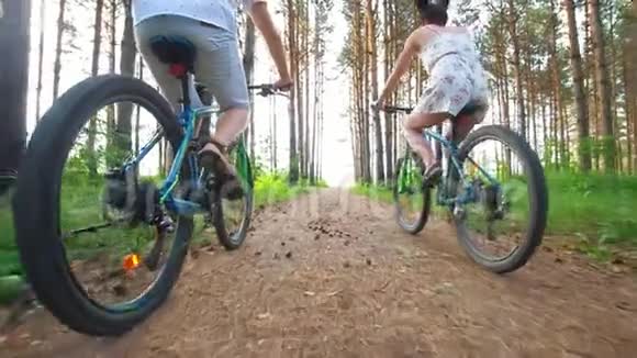 年轻夫妇骑自行车穿过夏季森林的后景视频的预览图