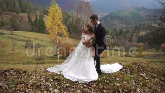 这对美丽的新婚夫妇在山里的秋村里温柔地拥抱着视频的预览图